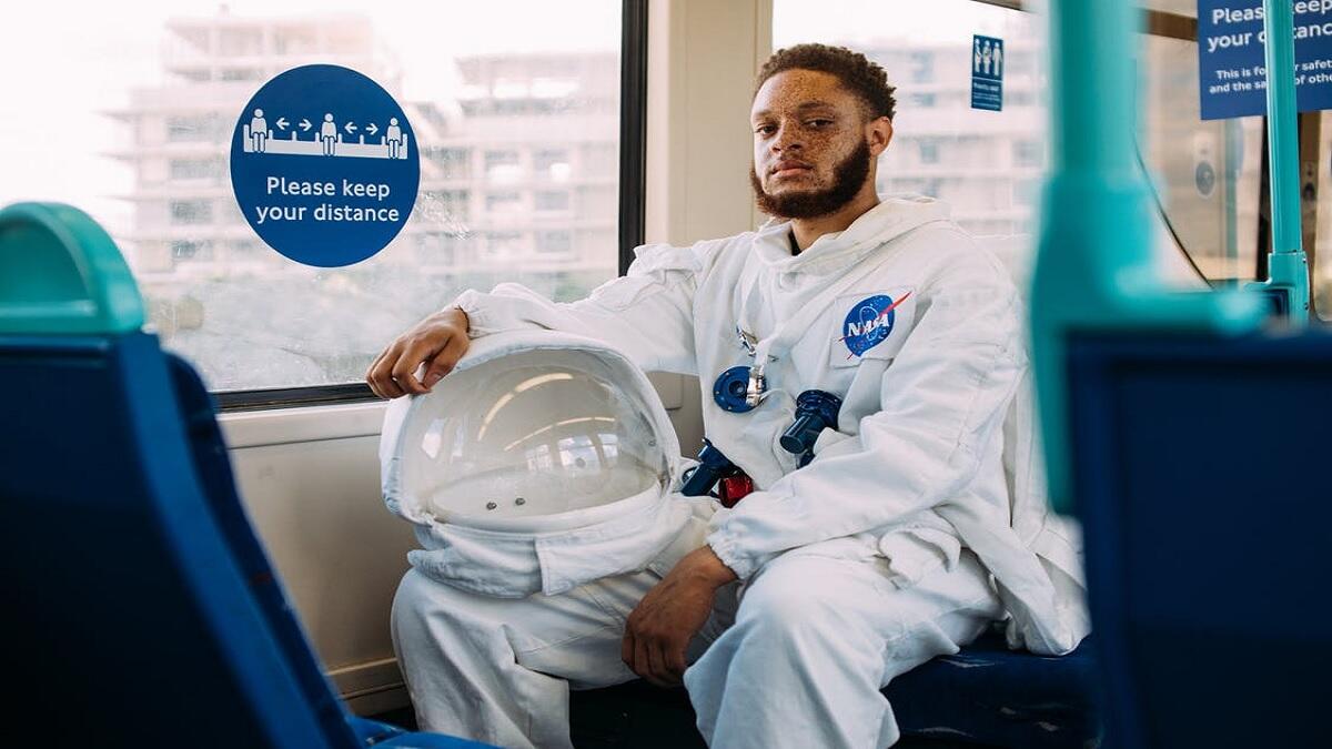 An astronaut wearing his costume as he takes a ride with a train